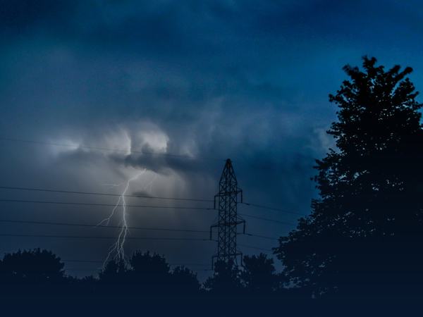 Lightning storm over power lines during an outage that calls for emergency ice delivery